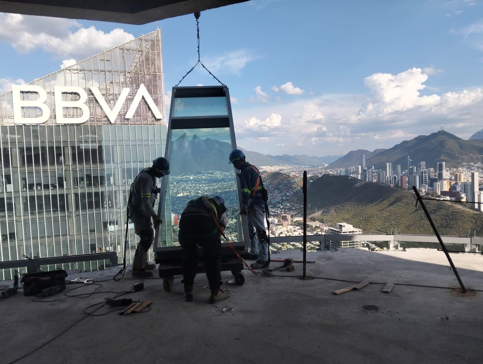 Cuadrilla de VECA colocando una unidad de vidrio en la torre Rise, con la Sierra Madre al fondo